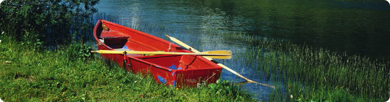 Red rowboat by the side of a river
